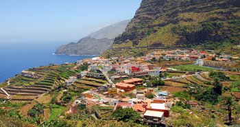 Vista panorámica de Agulo con sus tejados rojos entre acantilados y el mar, con el Teide al fondo, en La Gomera