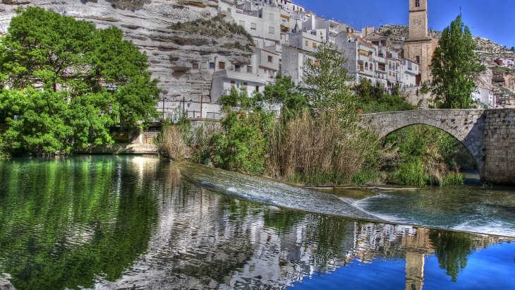Vista panorámica de Alcalá del Júcar colgado en la ladera de la hoz sobre el meandro del río Júcar