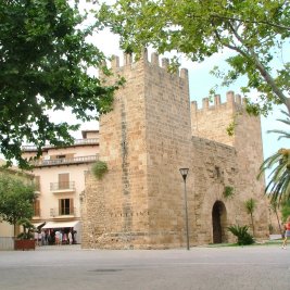 Murallas medievales de Alcúdia al atardecer, con la Porta de Mallorca y los tejados del casco antiguo del pueblo mallorquín
