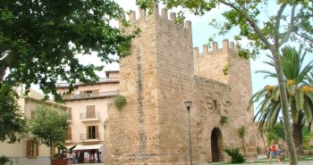 Murallas medievales de Alcúdia al atardecer, con la Porta de Mallorca y los tejados del casco antiguo del pueblo mallorquín