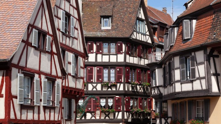 Casas de entramado de madera y colores junto a un canal florido en Colmar, Alsacia