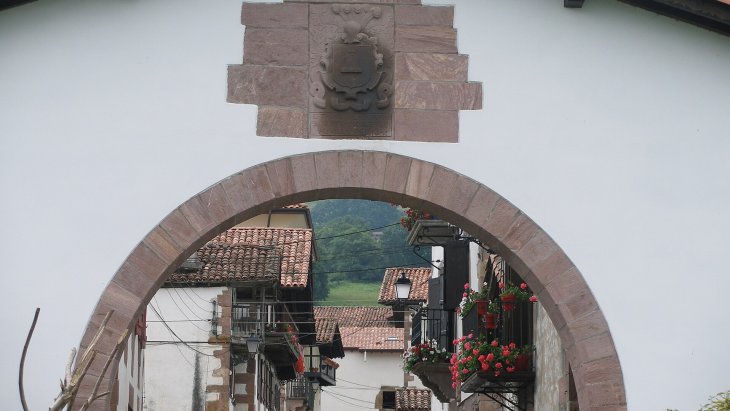 Calle principal de Amaiur con sus caseríos blasonados del valle de Baztan y colinas verdes al fondo