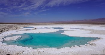 Laguna altiplánica turquesa con volcanes al fondo en el desierto de Atacama