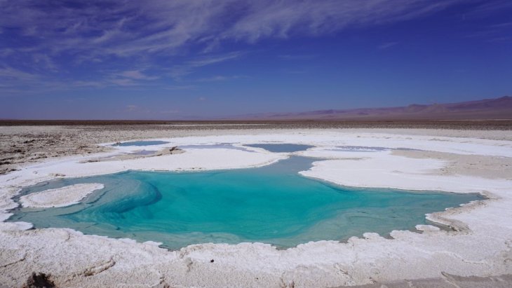 Laguna altiplánica turquesa con volcanes al fondo en el desierto de Atacama