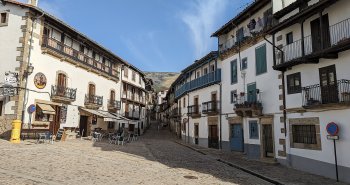 Calle empinada de Candelario con casas serranas de piedra y la Sierra de Béjar al fondo