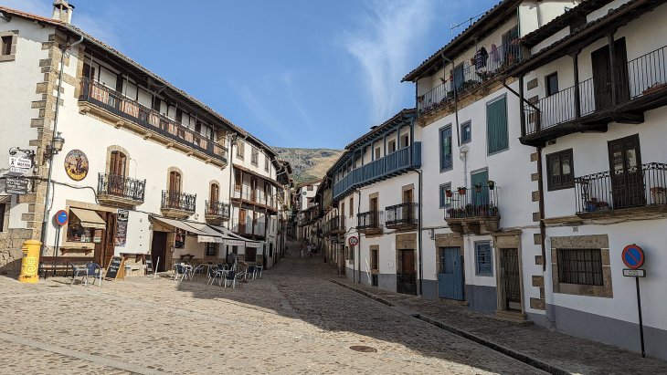 Calle empinada de Candelario con casas serranas de piedra y la Sierra de Béjar al fondo
