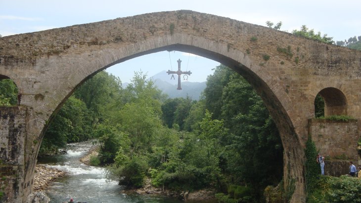 Puente romano de Cangas de Onís sobre el río Sella, con la Cruz de la Victoria colgando de su arco central