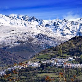 Casas blancas de Capileira escalonadas en la ladera del Barranco de Poqueira, con las cumbres de Sierra Nevada al fondo