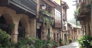 Calle empedrada de Cartes con sus torreones medievales y casonas de balcones de madera
