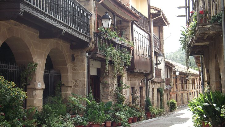 Calle empedrada de Cartes con sus torreones medievales y casonas de balcones de madera