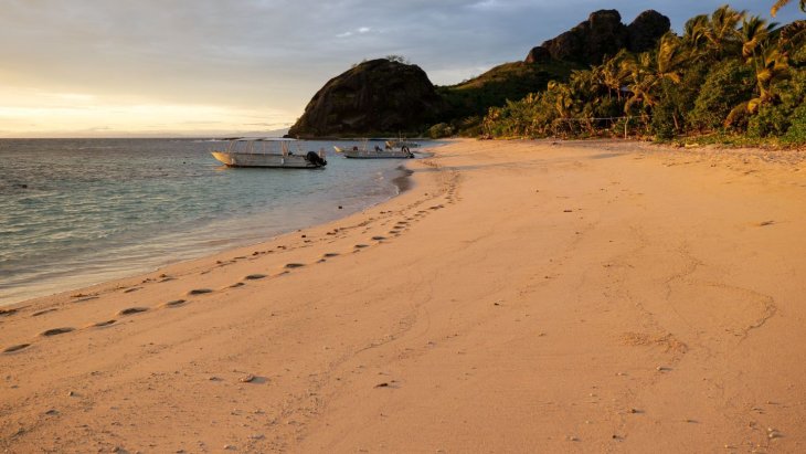 Playa de arena blanca con palmeras y aguas turquesas en una isla de Fiyi