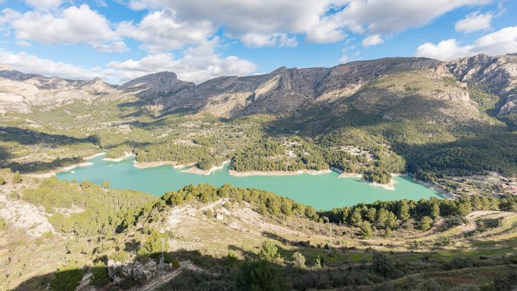 Vista panorámica del Castell de Guadalest con el campanario blanco sobre la peña y el embalse turquesa al fondo