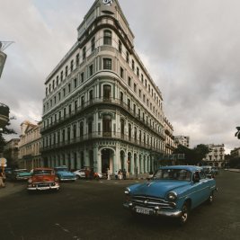 Coches clásicos de colores circulando frente a las fachadas de La Habana