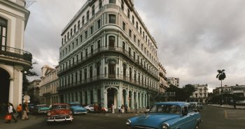 Coches clásicos de colores circulando frente a las fachadas de La Habana