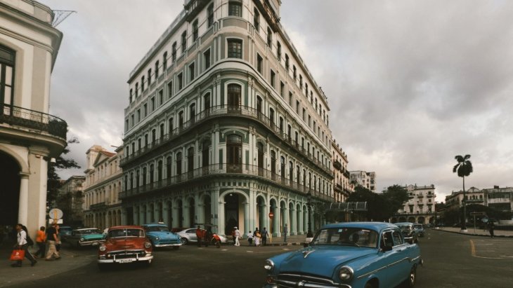 Coches clásicos de colores circulando frente a las fachadas de La Habana