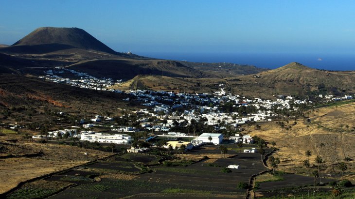 Vista panorámica del valle de las mil palmeras de Haría, con casas blancas entre palmerales y montañas volcánicas, en Lanzarote