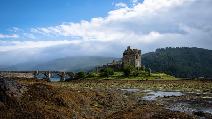 Castillo de Eilean Donan reflejado en el lago al atardecer, Highlands de Escocia