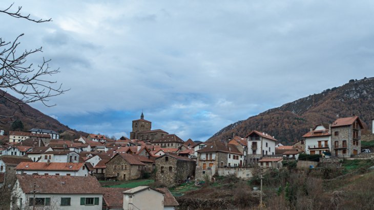 Vista panorámica de Isaba con sus tejados de piedra bajo la iglesia-fortaleza de San Cipriano y las montañas del Pirineo