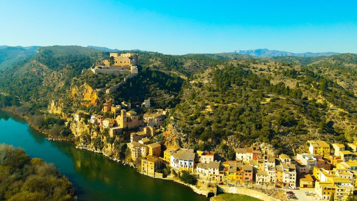 Panorámica de Miravet con sus casas sobre el río Ebro y el castillo templario en la cima