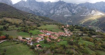 Aldea de Mogrovejo con su torre medieval y las casas de piedra ante las cumbres de los Picos de Europa