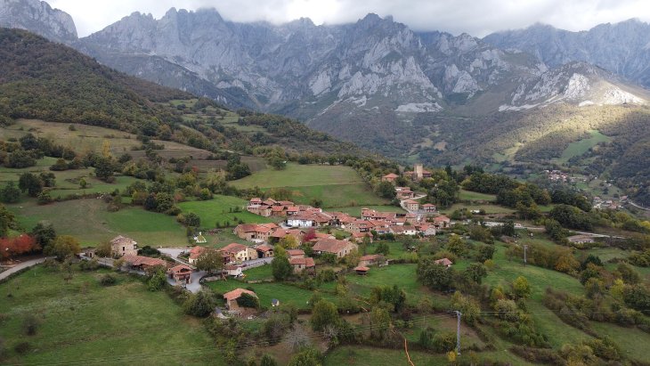 Aldea de Mogrovejo con su torre medieval y las casas de piedra ante las cumbres de los Picos de Europa
