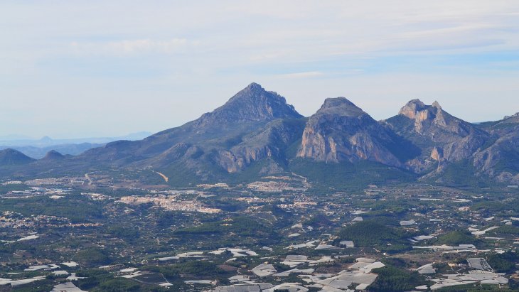 Vista panorámica de Polop de la Marina sobre su colina, con la sierra del Ponoig al fondo