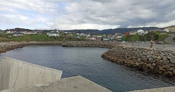 Puerto pesquero de Puerto de Vega en Asturias, con lanchas amarradas al abrigo del dique y casas marineras al fondo