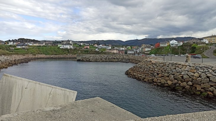 Puerto pesquero de Puerto de Vega en Asturias, con lanchas amarradas al abrigo del dique y casas marineras al fondo