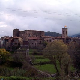 Vista del pueblo medieval de Santa Pau con su castillo y campanario entre los paisajes volcánicos de la Garrotxa