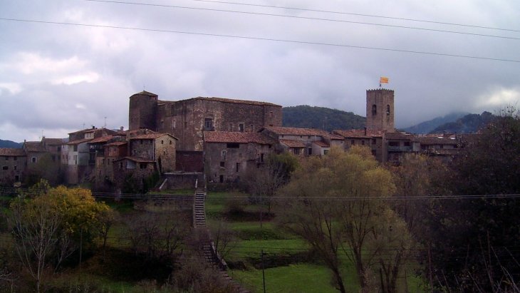 Vista del pueblo medieval de Santa Pau con su castillo y campanario entre los paisajes volcánicos de la Garrotxa