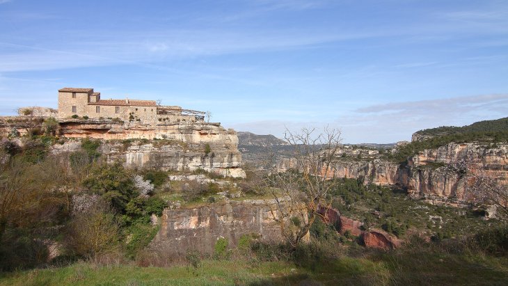 Vista de Siurana en lo alto de su risco calizo con el embalse turquesa al fondo