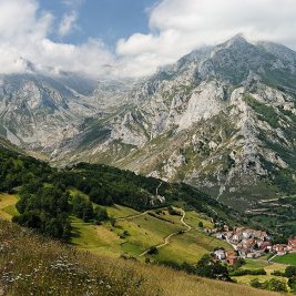 Panorámica de Sotres, el pueblo más alto de Asturias, con sus casas de piedra en la ladera y las cumbres de los Picos de Europa detrás