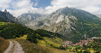 Panorámica de Sotres, el pueblo más alto de Asturias, con sus casas de piedra en la ladera y las cumbres de los Picos de Europa detrás