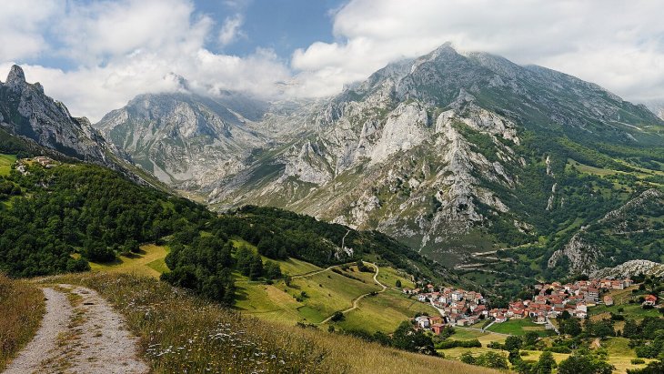 Panorámica de Sotres, el pueblo más alto de Asturias, con sus casas de piedra en la ladera y las cumbres de los Picos de Europa detrás