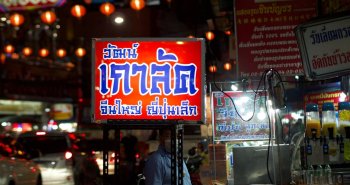 Puesto de comida callejera humeante en una calle de Bangkok