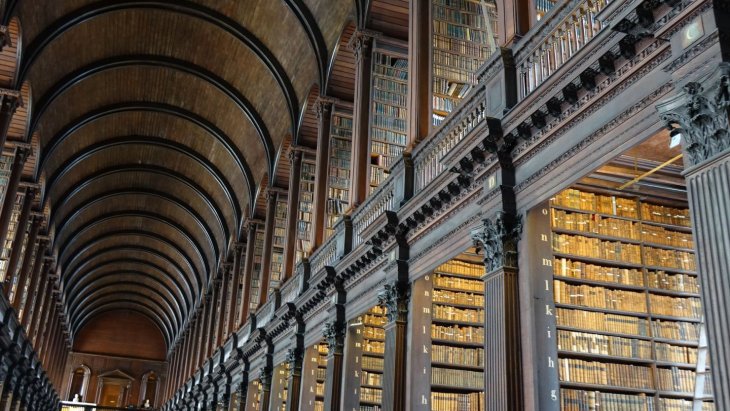 Sala histórica de una biblioteca con estanterías de madera repletas de libros antiguos