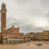 Gran plaza histórica europea rodeada de fachadas antiguas y llena de ambiente