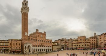 Gran plaza histórica europea rodeada de fachadas antiguas y llena de ambiente