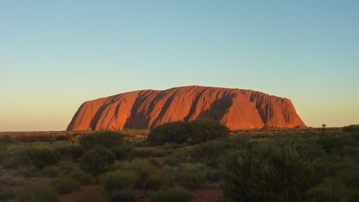 El monolito de Uluru teñido de rojo al atardecer en el desierto australiano