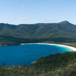 Vista de Wineglass Bay en Tasmania, con su playa curva de arena blanca rodeada de montañas y bosque