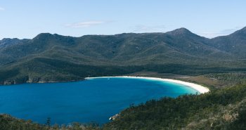 Vista de Wineglass Bay en Tasmania, con su playa curva de arena blanca rodeada de montañas y bosque