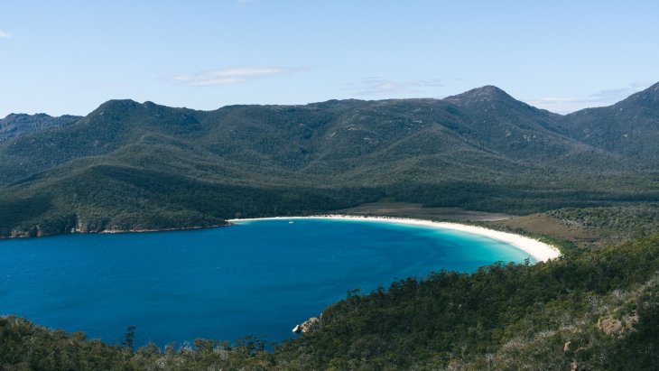 Vista de Wineglass Bay en Tasmania, con su playa curva de arena blanca rodeada de montañas y bosque